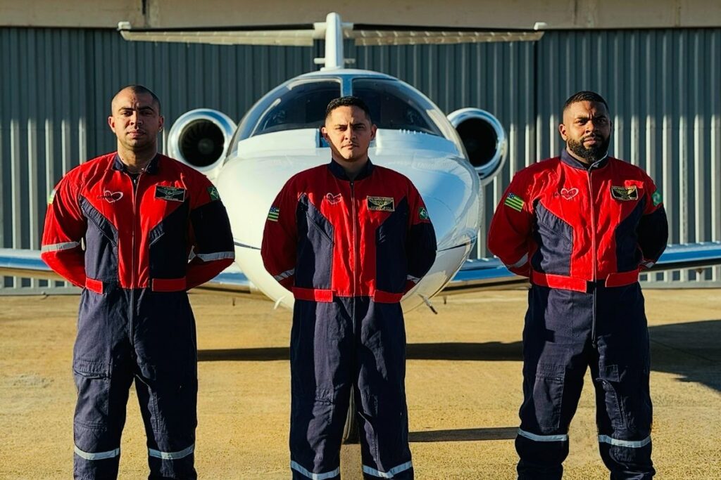 Homens posando para foto de braços cruzados em frente ao avião
