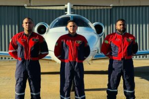 Homens posando para foto de braços cruzados em frente ao avião