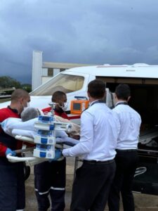 Médicos colocando paciente em avião para transporte