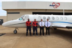 Time da Brasil Vida olhando para a câmera em frente ao jato da empresa