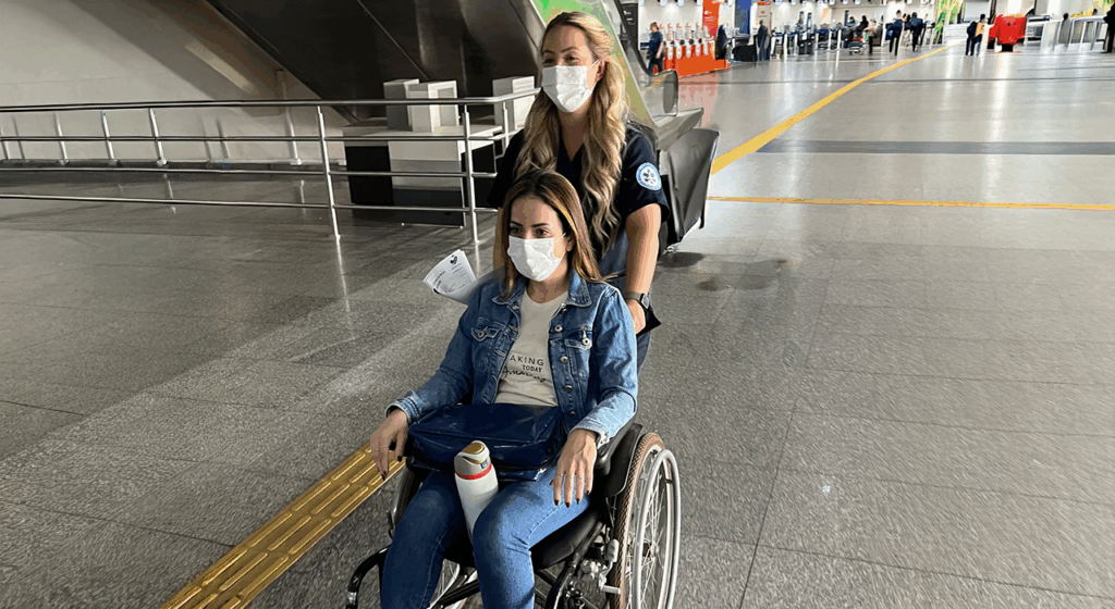 Serviço de Medical Escort acompanhando paciente em cadeira de rodas durante embarque em voo comercial.