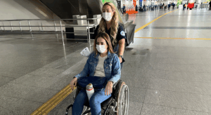 Serviço de Medical Escort acompanhando paciente em cadeira de rodas durante embarque em voo comercial.