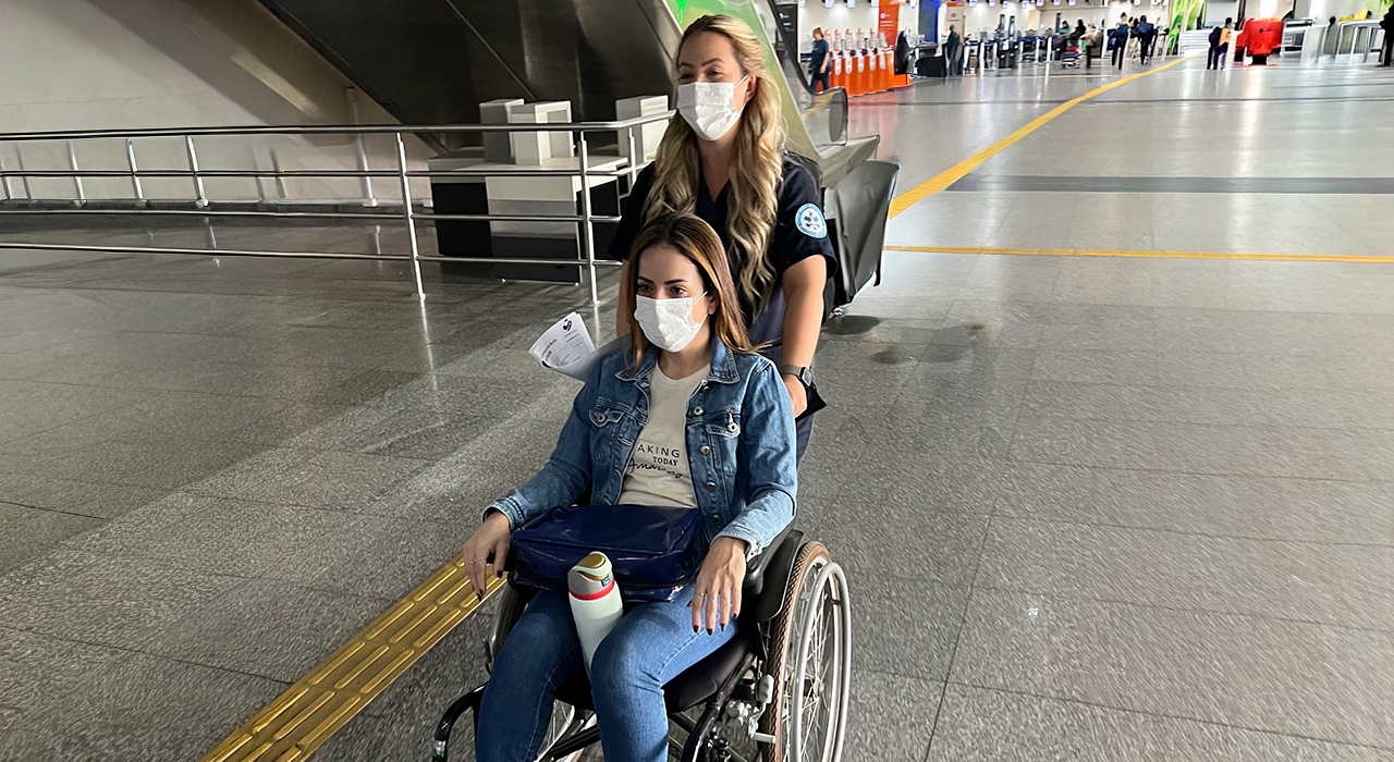 Serviço de Medical Escort acompanhando paciente em cadeira de rodas durante embarque em voo comercial.