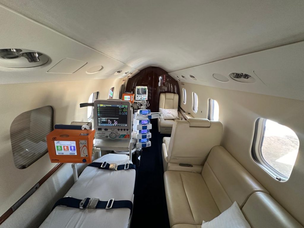 Interior de ambulância aérea com maca, monitores e equipamentos médicos para transporte aeromédico de pacientes.